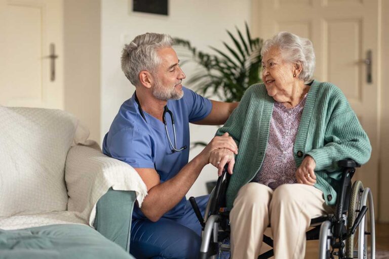 Older adult smiling at a dining table alongside others in a comfortable assisted living common area.