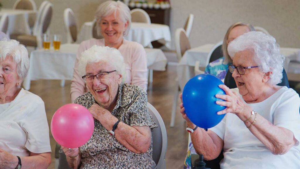 Older adults share a meal and follow a calm daily schedule in an assisted living dining room.
