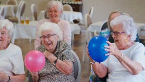 Older adults share a meal and follow a calm daily schedule in an assisted living dining room.